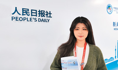 图为记者在新闻中心持《人民日报海外版》留念。本报记者 徐佩玉摄